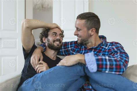 Loving Same Sex Male Gay Couple Lying On Sofa At Home And Relaxing Cuddling Together