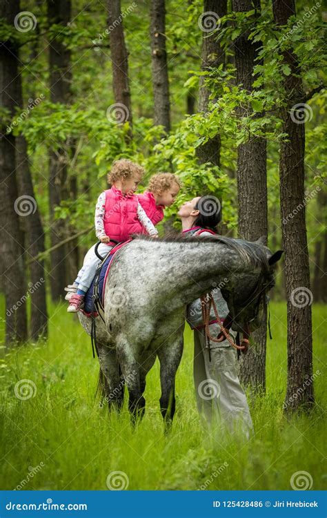 Girls Enjoying Horseback Riding In The Woods With Mother Young Pretty