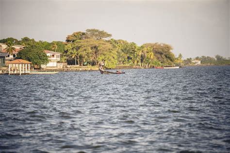 Boat On The Sea Surface With Trees And Houses On The Coast In Puerto