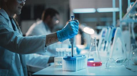 Female Research Scientist Uses Micropipette To Mix Liquids In A Sample