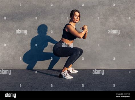 Image Of A Sportive Woman In Sneakers And A Tracksuit Squatting Doing