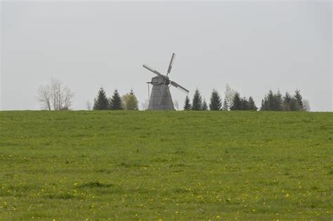 Un Molino De Viento En Un Campo Con Un Campo De Rboles Al Fondo