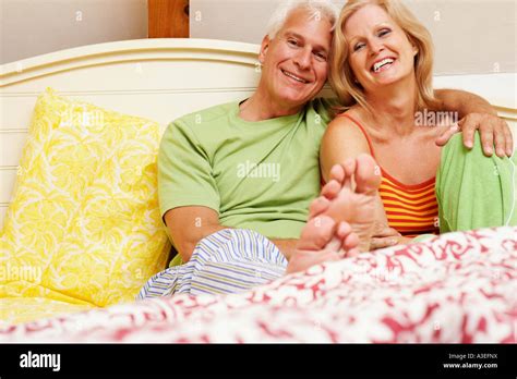 Portrait Of A Mature Couple Sitting On The Bed And Smiling Stock Photo Alamy