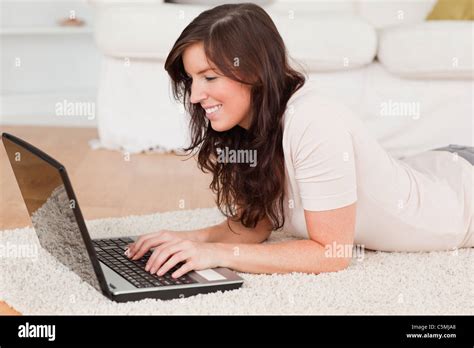 Attractive Brunette Woman Relaxing With Her Laptop While Lying On A Carpet Stock Photo Alamy