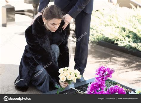 Pareja Poniendo Flores En La Tumba De Su Pariente En El Funeral Fotografía De Stock © Serezniy