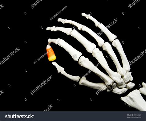 Skeleton Hand Holding A Piece Of Candy Corn Isolated On A Black ...