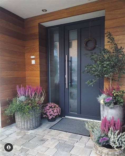 Some Plants Are Sitting In Front Of A Door And Two Baskets With Flowers