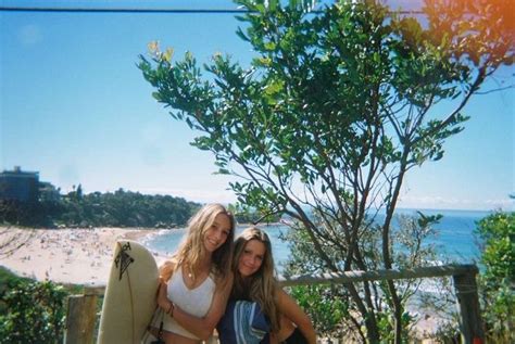 Two Women Standing Next To Each Other Holding Surfboards In Front Of