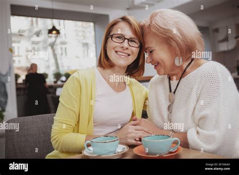 Happy Mature Woman Smiling Joyfully To The Camera Cuddling With Her Senior Mother Elderly