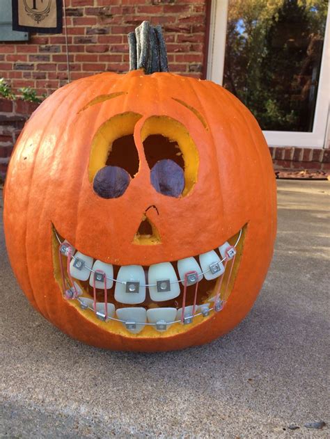 A Carved Pumpkin With Teeth And Braces On It S Front Porch For Halloween