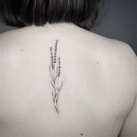 The Back Of A Woman S Neck With A Flower Tattoo On It