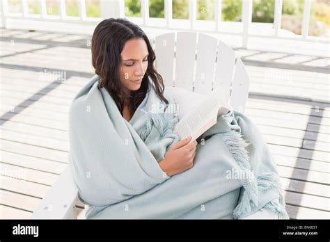 Pretty Brunette Sitting On A Chair And Reading A Book Stock Photo Alamy