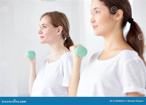 Pregnant Ladies Lifting Weights Using Dumbbells In Fitness Center