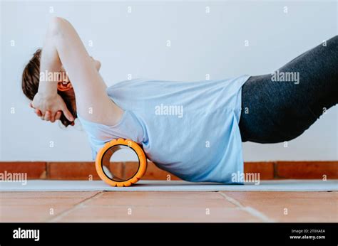 Woman Rolling Back On A Foam Massage Roller To Release Tension In Back