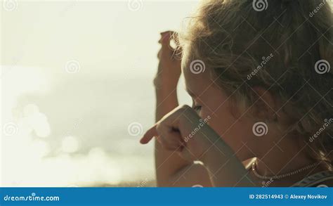 Portrait Of A Happy Blonde Little Girl Playing With Pebble On The Beach