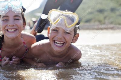 Brother And Sister Wearing Goggles And Laying In Ocean Stock Image