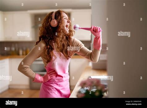 Redhead Woman Washing Dishes In The Kitchen And Listening To Music By