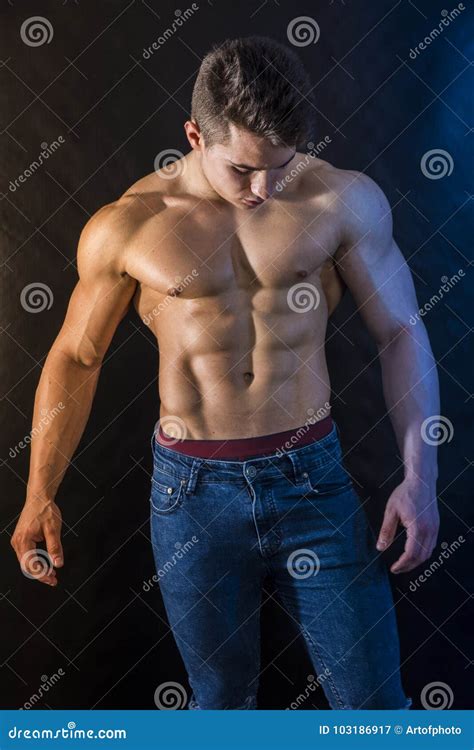 Muscleman Joven Que Se Coloca Descamisado En Fondo Negro Imagen De