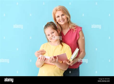 Mature Woman And Her Cute Granddaughter With Books On Color Background Stock Photo Alamy
