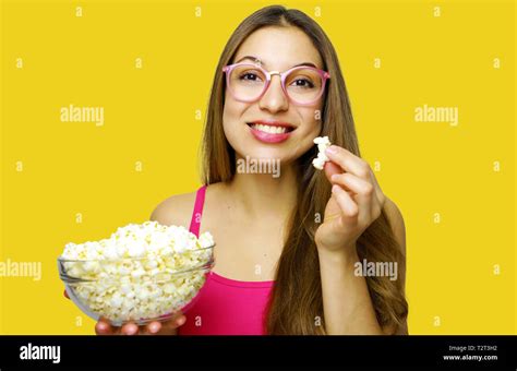 Happy Cheerful Woman Eating Pop Corn Looking To The Side On Yellow