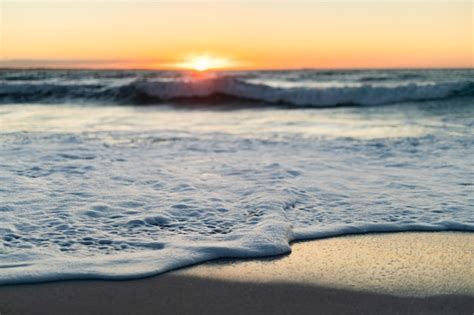 Vista De Una Playa De Arena Y Un Mar Tranquilo Con Olas Y Cielo Azul Al