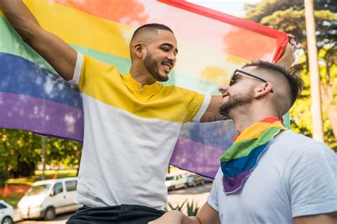 Homopaar Omarmt En Toont Zijn Liefde Voor De Regenboogvlag Stock