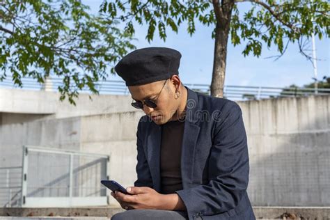 Un Joven Gay Latino Con Un Sombrero De Moda Y Gafas De Sol Mandando Mensajes De Texto En Su