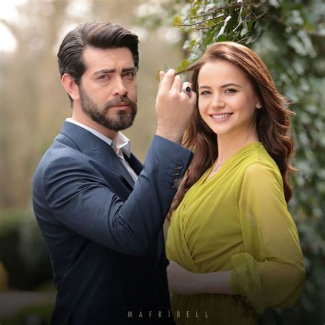 A Man And Woman Are Posing For A Photo In Front Of Some Bushes One Is