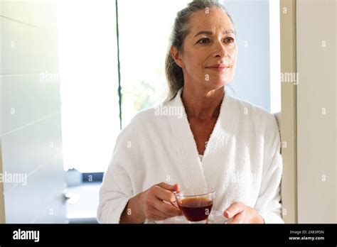 At Bathroom At Home Caucasian Mature Woman Holding Tea Standing By Window Stock Photo Alamy