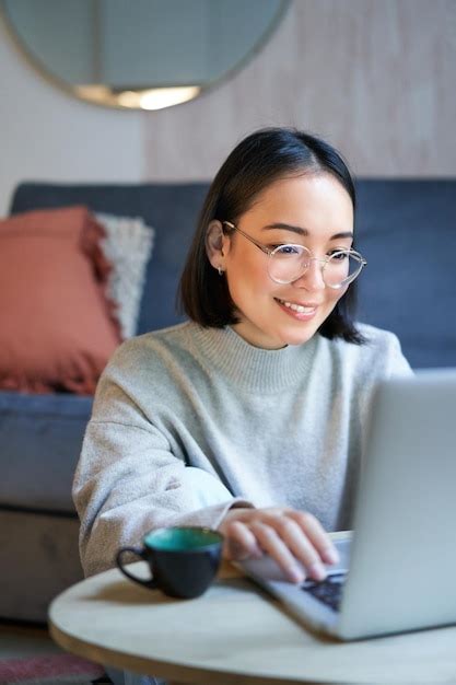 Jovem asiática freelancer profissional sentada na sala de estar e