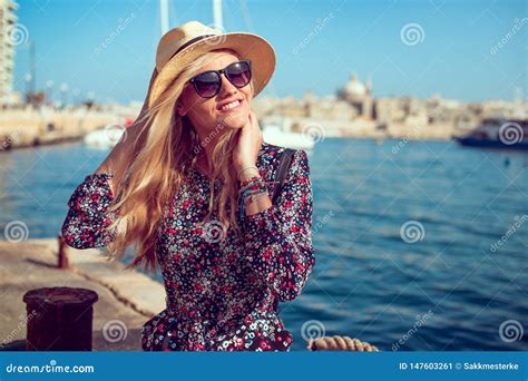 Femme Méditerranéenne Blonde Heureuse Dans Le Chapeau Posant En Mer Dans La Ville Image stock