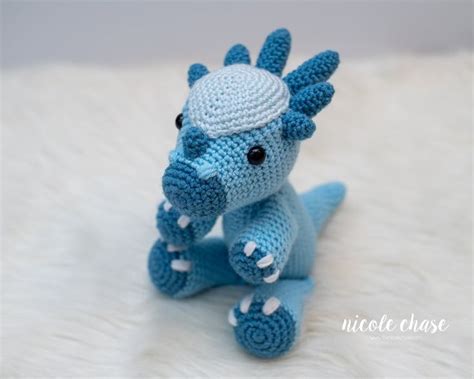 A Crocheted Blue Dragon Sitting On Top Of A White Furnishing Area