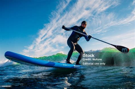 Stand Up Paddle Surfing On Waves Surfer In Wetsuit With Paddle Ride On