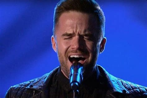 A Man Singing Into A Microphone On Stage