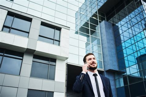 Joven empresario en un traje azul hablando por un teléfono celular