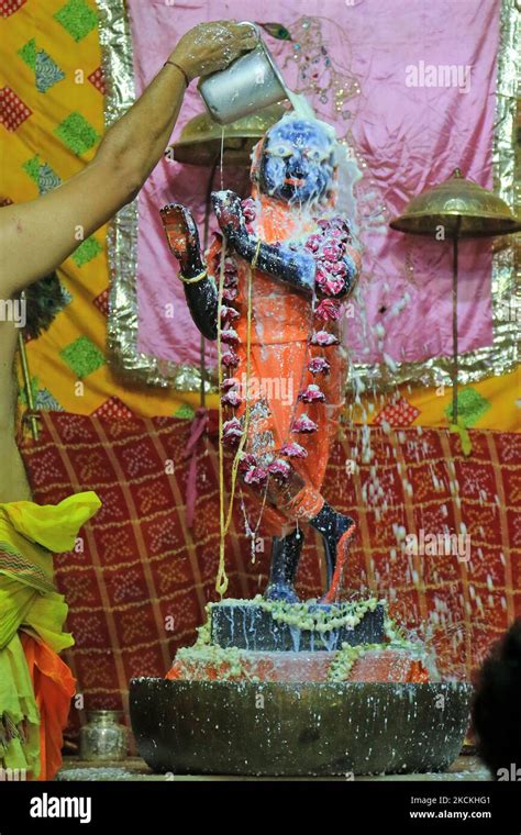 A priest performs 'Abhishek' to Lord Krishna on the occasion of ...