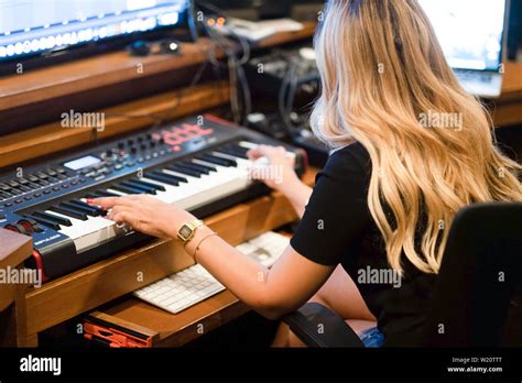 Blonde Female Musician Playing Keyboards In A Musical Studio While