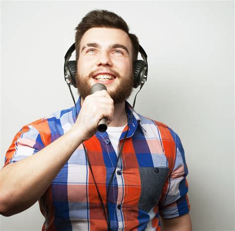 A Young Man With A Beard Wearing A Plaid Shirt Holding A Microphone And Singingisolated On