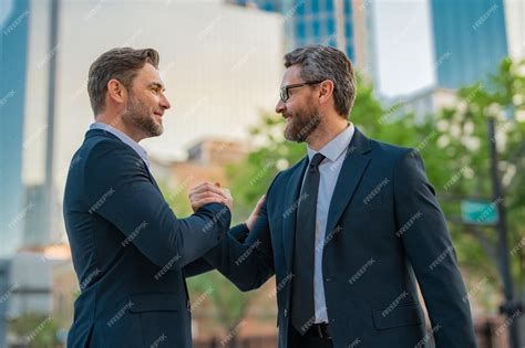 Premium Photo | Two businessmen shaking hands on city street business ...