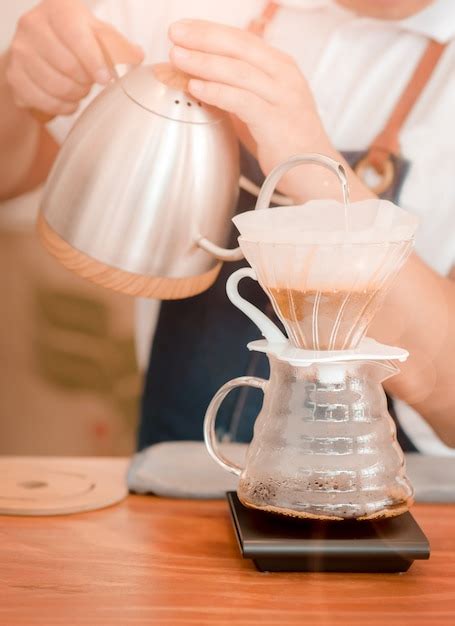 Barista segurando derrama água quente fervida em uma cafeteira Foto