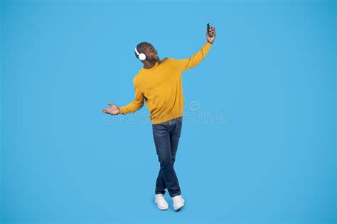 Positive Black Man Listening To Music And Dancing Using Smartphone