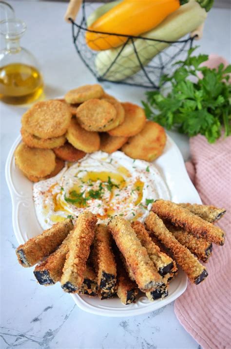 An Assortment Of Appetizers On A Plate With Dip And Vegetables In The