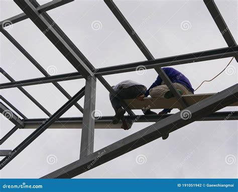 Two Structural Steel Workers Working On A High Rooftop For A House Roof