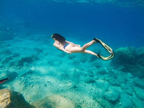 Hermosa mujer nadando bajo el agua con máscara de snorkel y aletas