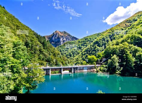 dam with blue and green water forms a small lake in the midst of ...