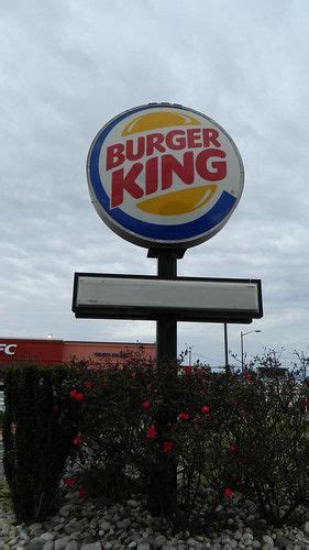 a burger king sign in front of some bushes