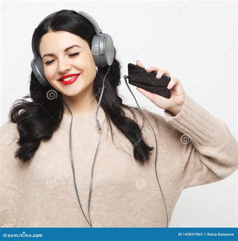 Νέα Curvy γυναίκα Brunette στα ακουστικά που ακούει τη μουσική Στοκ Εικόνα εικόνα από