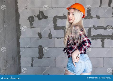 Belle Fille La Blonde D Agent De Ma Trise De Concepteur Dans Un Casque Orange De Construction Et