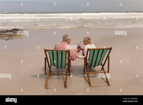 Senior Couple Toasting Glasses Of Cocktail Drinks In A Sun Lounger