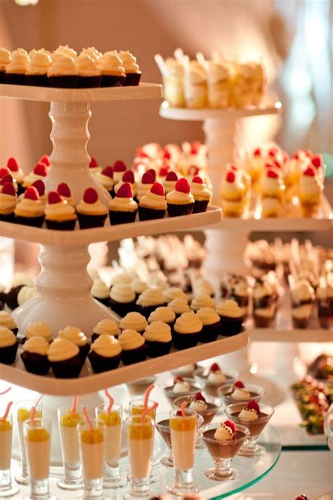 An Assortment Of Cupcakes And Desserts Are Displayed On Three Tiered Trays